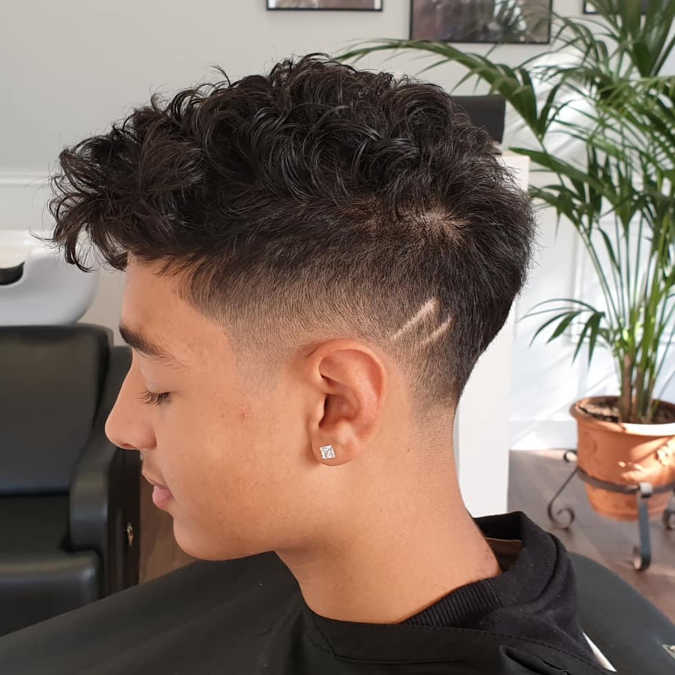 Corte curly fade con diseño lateral